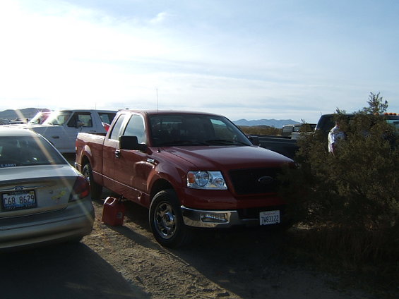 Red 2004 Ford F-150 pickup truck with a red gas can underneath