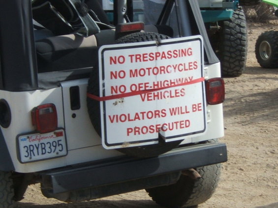 Rear view of a Jeep Wrangler with a 'No Trespassing' sign attached to the spare tire