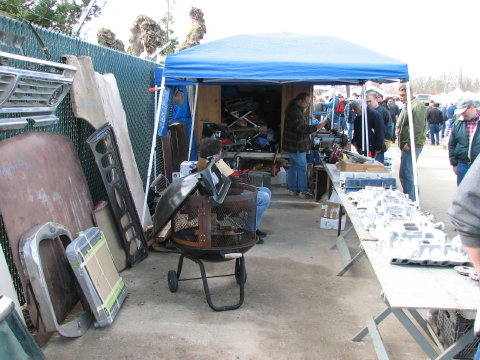 Car parts including hoods and grilles displayed at an outdoor market
