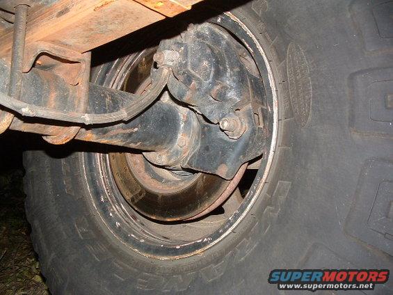 Rear axle assembly and tire of a vehicle, showing rust and wear
