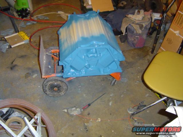 Blue engine block on an orange and black cart in a workshop