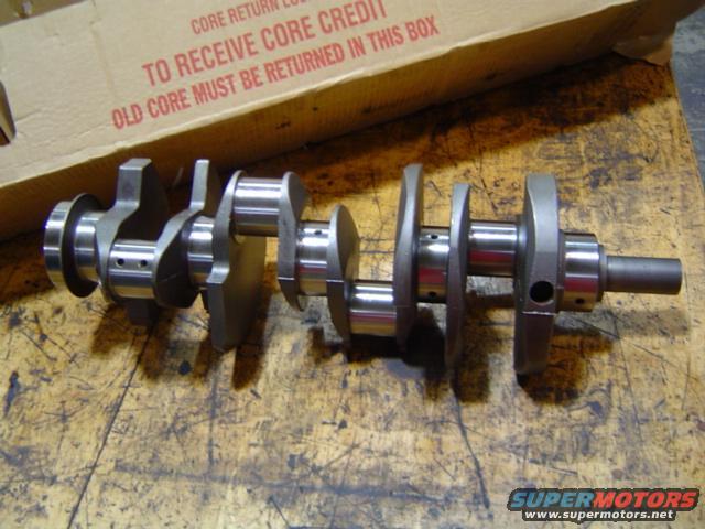 Crankshaft on a wooden surface with a cardboard box in the background