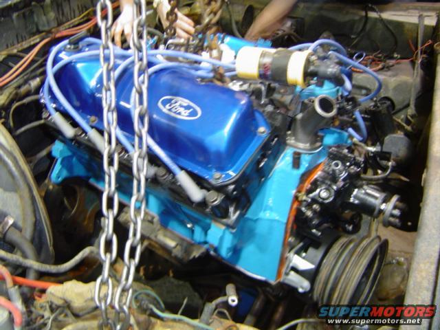 Ford V8 engine with blue valve covers and chains attached for lifting