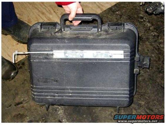 Person holding a black plastic case with metal hinges and latches