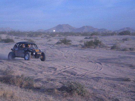 Black off-road buggy with number 577 on door driving in desert