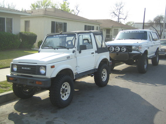 1987 Suzuki Samurai and a white Ford Bronco parked on street