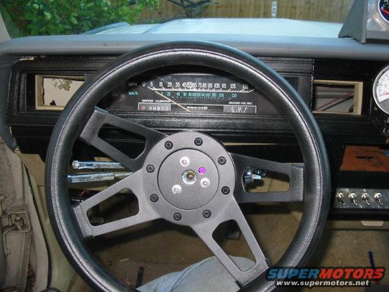 Aftermarket steering wheel in a car interior, showing the dashboard and gauges