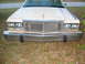 1985 Ford Crown Victoria LTD - The front grille and headlights of a beige Ford sedan are visible, parked on grass.