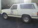 1988 Ford Bronco - A white SUV is parked in front of a garage, with another vehicle visible inside.