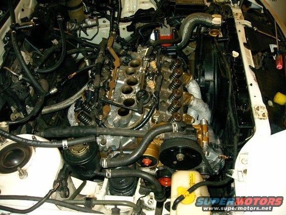 Engine bay with V6 engine exposed, hoses and wiring visible