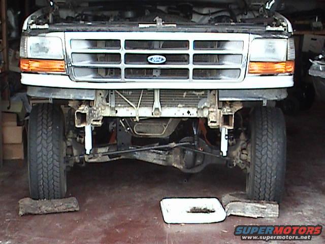 Front of a 1992 Ford F-Series truck with hood up, bumper removed, and front tires on blocks