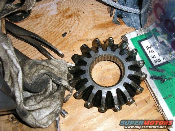 Differential gear with 15 teeth on a wooden surface next to a greasy rag and pliers