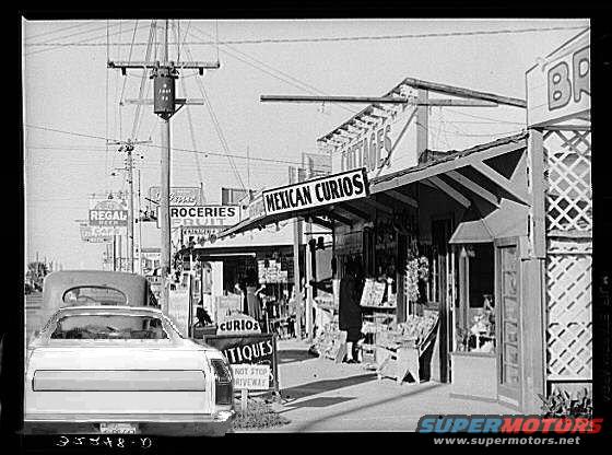 Rear view of a 1970s pickup truck parked on a street with shops