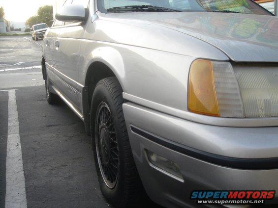 1991 Ford Taurus front quarter panel and wheel, parked on asphalt