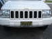 1997 Jeep Grand Cherokee - Front view of a white 1997 Jeep Grand Cherokee, showing its grille, headlights, and license plate.