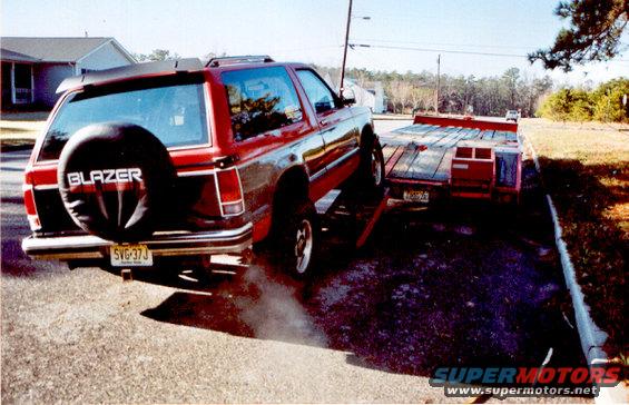 Red 1989 Chevrolet S10 Blazer with a spare tire on the rear, hitched to a red trailer