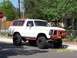 1978 Ford Bronco - A lifted 1978 Ford Bronco with a custom red bumper and orange roof sits on a street.