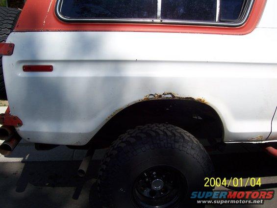 White and red 1978 Ford Bronco rear side with rust around the wheel well and a spare tire mounted on the back