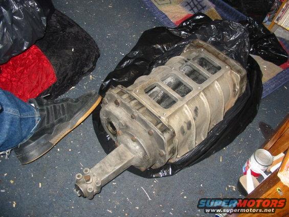 supercharger sitting on the floor next to a person's foot and some bags