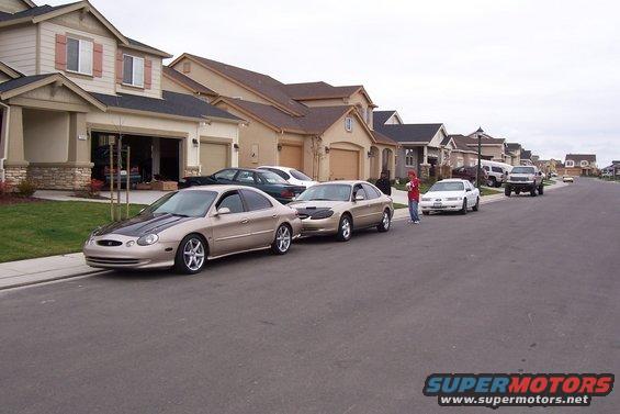 1998 Mercury Sable with aftermarket black hood parked on suburban street, other cars visible