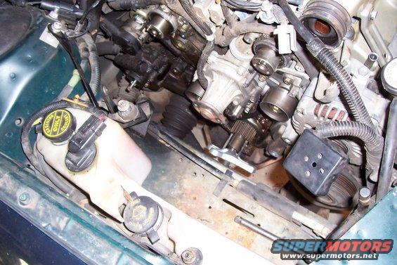Engine bay with coolant reservoir and various engine components. Green exterior paint visible