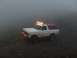 1978 Ford Bronco - A 1978 Ford Bronco is driven through a foggy, rocky terrain with its headlights and roof lights illuminated.