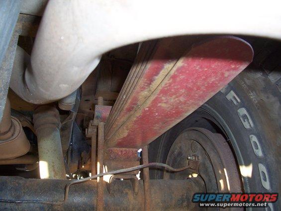 Close-up of a red leaf spring assembly and tire on a vehicle's undercarriage