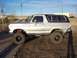 1978 Ford Bronco - This lifted 1978 Ford Bronco is shown from the side, parked on a dirt lot with a clear blue sky above.