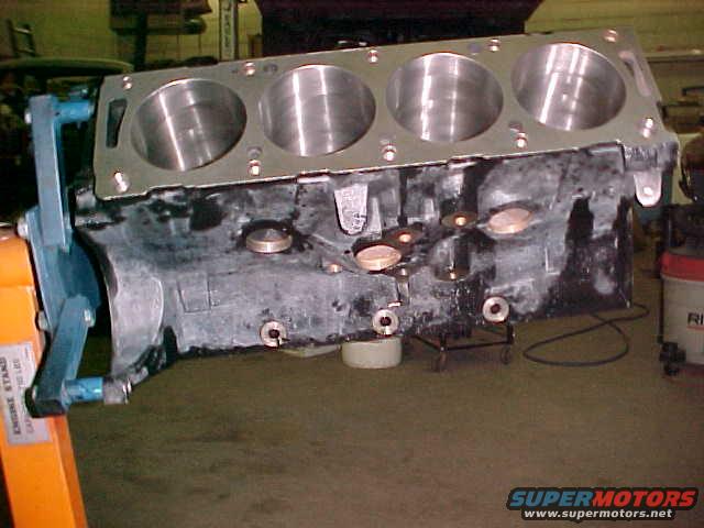 Engine block on an orange engine stand, showing cylinder bores