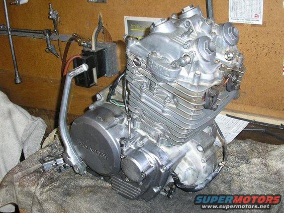Honda motorcycle engine on a workbench with a kickstarter lever