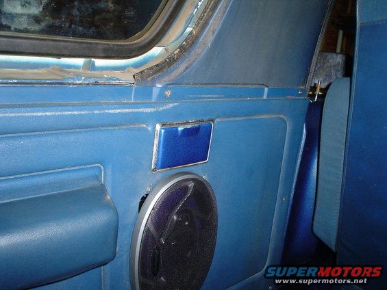 Blue interior door panel with a speaker and a small blue accent piece