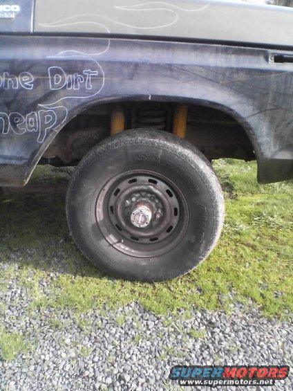 1978 Ford Bronco rear wheel and fender with custom paint. Yellow shocks visible