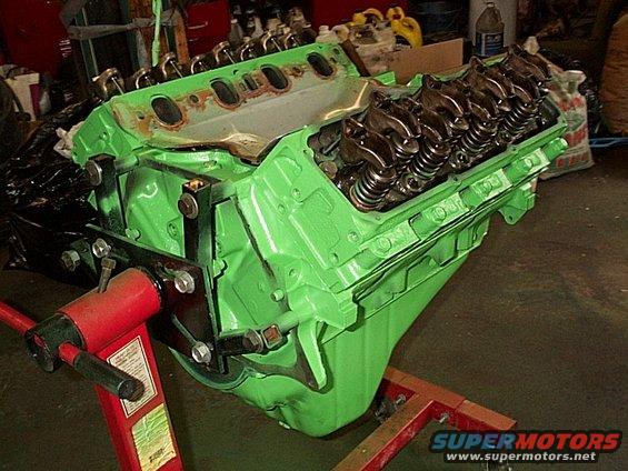 Green V8 engine block on a red engine stand in a garage