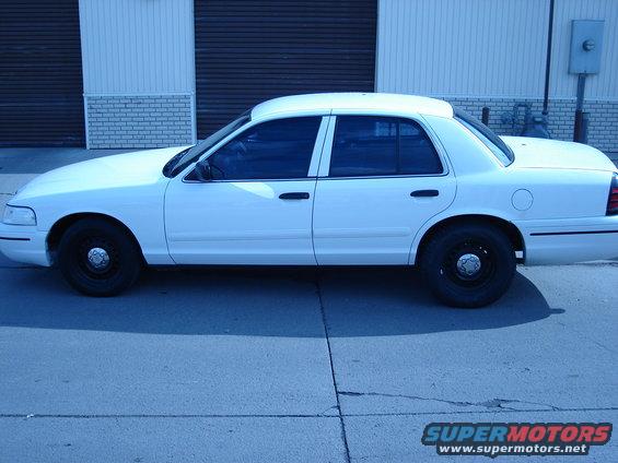 White 2000 Ford Crown Victoria sedan, side view, black steel wheels, tinted windows, parked on asphalt