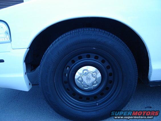White car wheel with Ford badge on hubcap, close-up of front fender