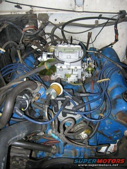Engine bay showing carburetor, spark plug wires, and hoses