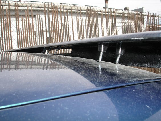 Carbon fiber spoiler bolted to a blue car's trunk lid