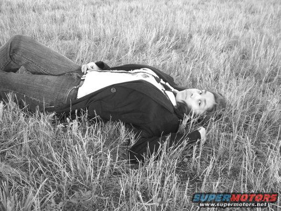Person in jeans and jacket lying on their back in tall grass