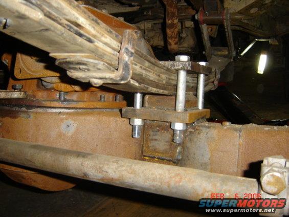Close-up of a vehicle's leaf spring with added U-bolts and plates