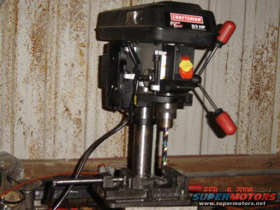 Craftsman drill press with red handles and a drill bit