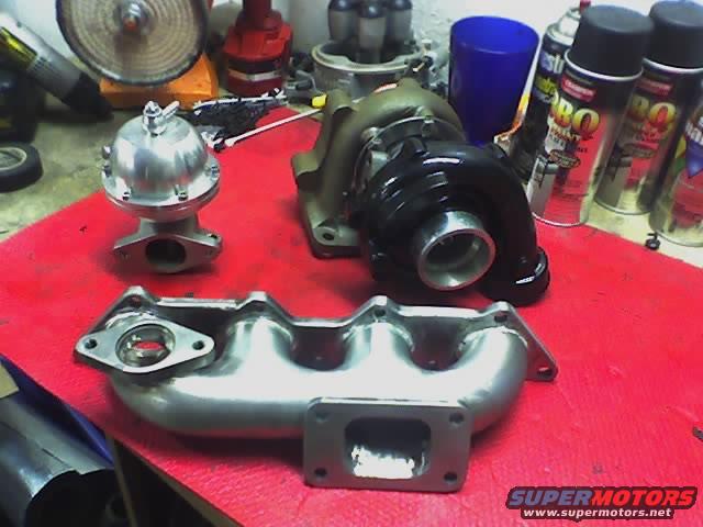 Turbocharger, wastegate, and exhaust manifold on red surface