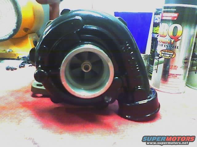 Black turbocharger with silver impeller housing, next to spray paint cans