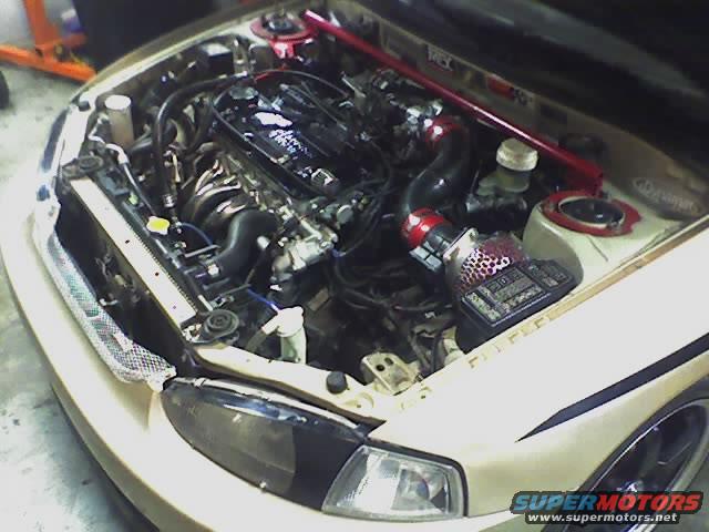 1999 Mitsubishi Mirage engine bay with aftermarket intake and red strut bar