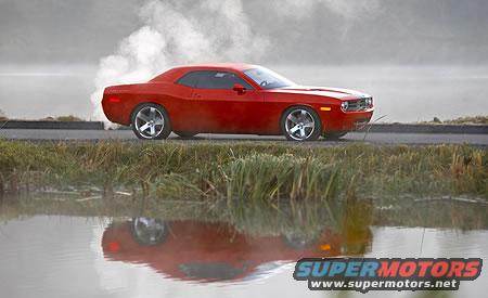 Red coupe with chrome wheels driving on a road, emitting smoke from the rear