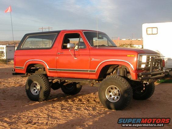 Red lifted 1984 Ford Bronco with black top and off-road tires