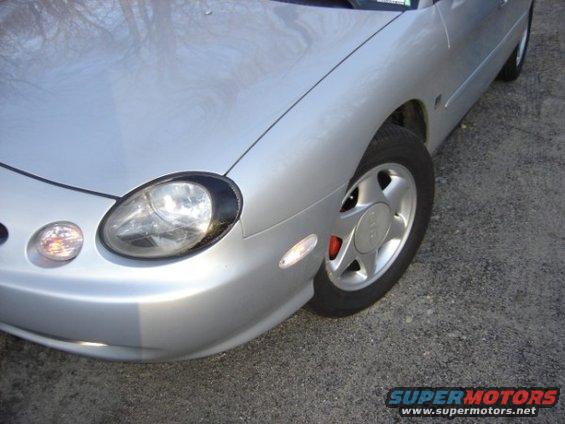 Front corner of a silver sedan, showing headlight, turn signal, and wheel