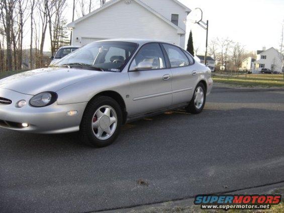Silver sedan parked on asphalt, front 3/4 view. Red brake calipers visible