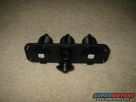 Black triple switch panel with two illuminated symbols and one central socket