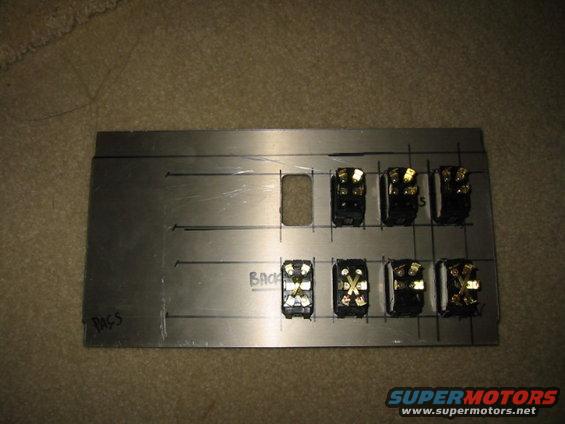 Metal panel with seven toggle switches and one blank cutout, marked with lines and 'PASS' and 'BACK'