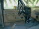 1989 Ford Bronco - The interior of a truck shows the driver's side door panel, steering wheel, and dashboard with a roll cage installed.